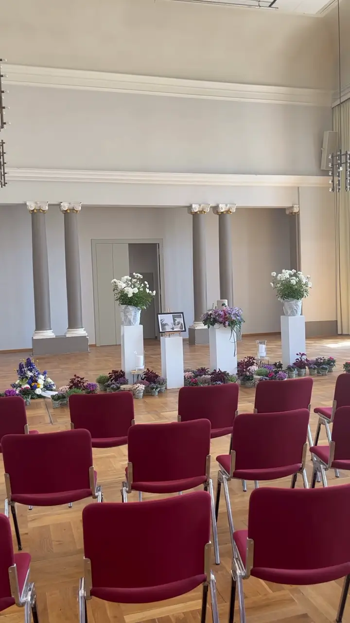 Blumen, Bild und Kerzen vor den Säulen im Saal der Orangerie